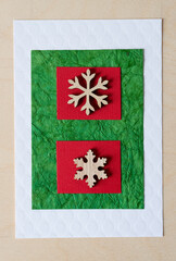 two wooden snowflake ornaments on red and green paper