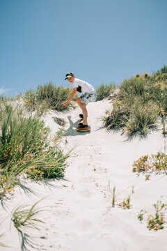 Riding a sandboard down a sandy hill at the beach for fun