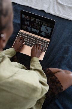 Black woman browsing photos on laptop