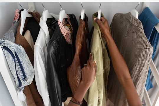 Crop black woman selecting trendy jacket