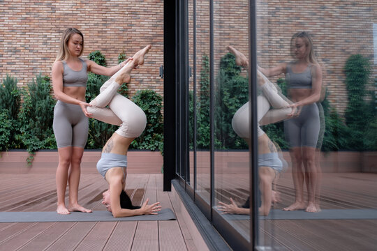 Woman supporting girlfriend during yoga session - Powered by Adobe