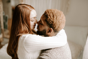 A young diverse couple laying in bed and home and cuddling