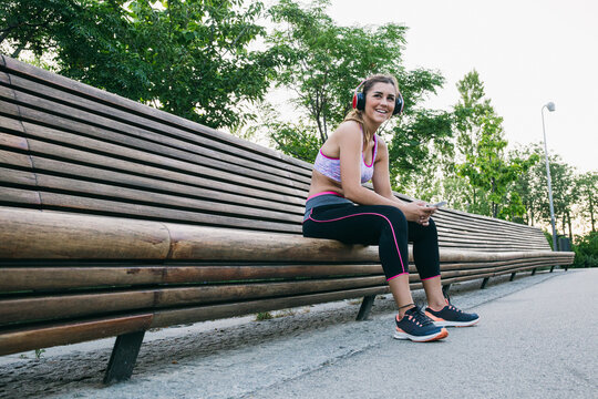 Woman listening to music on bench in park 