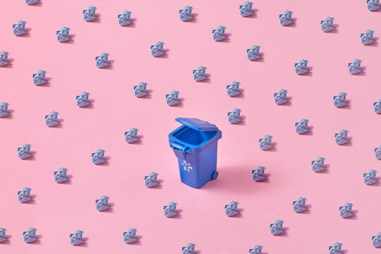 Blue trash can and scattered crumpled papers