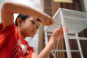 Little girl assembles a storage cabinet at home