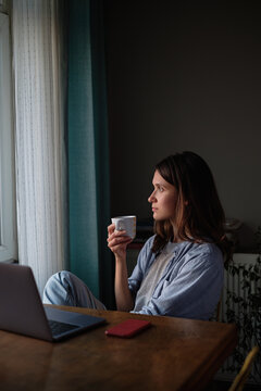 Woman with a coffee looking to the window at evening