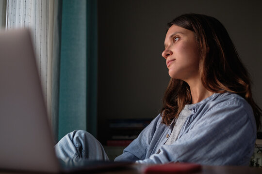 Woman looking to the window with laptop on the table