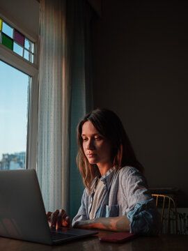 Woman working on laptop at home in the evening