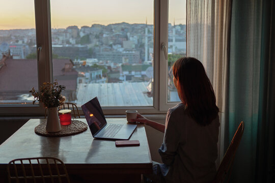 Woman looking to the window with laptop on the table
