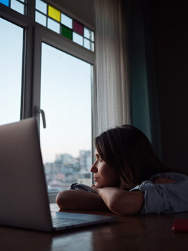 Woman looking to the window with laptop on the table