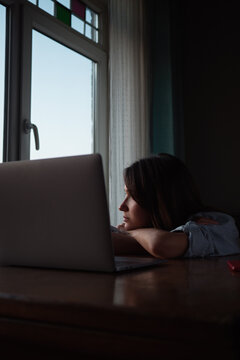 Woman looking to the window with laptop on the table