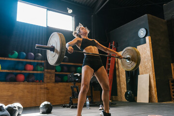 Sportswoman lifting a heavy barbell in the gymnasium