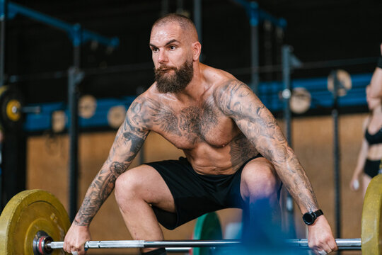 Tattooed man lifting weights at the gym