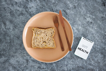 gut health notepad next to wholegrain multiseeds slice of bread on dining plate with fork and knife, healthy nutrition research about the microbiome