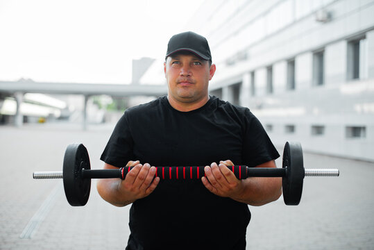 Man with a barbell on the background of a building