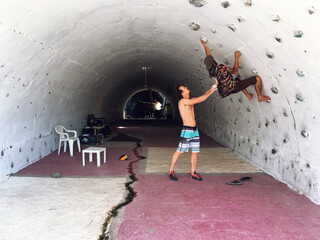 A climber assists his student to climb a boulder wall