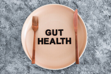 gut health text on dining plate with fork and knife, healthy nutrition and research about the...