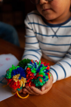 Child showing wool pompons handmade