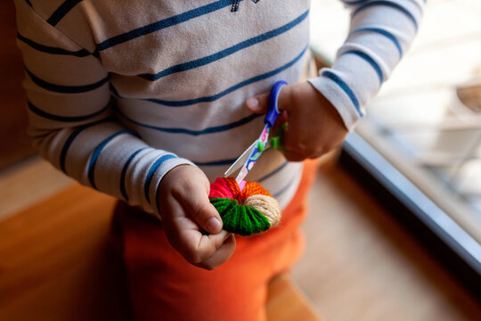 Kid making wool pompons