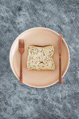 wholegrain multiseeds slice of bread on dining plate with fork and knife, dieting vs healthy nutrition and intuitive eating