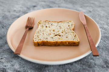wholegrain multiseeds slice of bread on dining plate with fork and knife, dieting vs healthy nutrition and intuitive eating