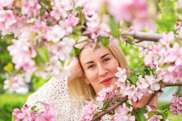 Obraz na płótnie Canvas Young woman among the blossoming trees. Spring nature park or garden, flowering trees. Concept spring woman health