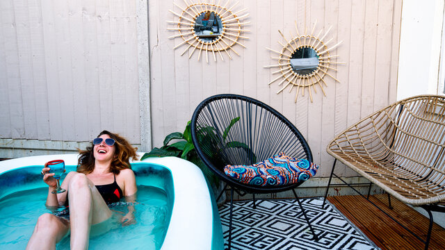 Young woman chilling with a drink in her inflatable pool