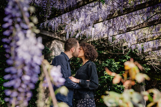 Sweet couple kissing in wisteria park