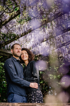 Sweet couple in embrace in wisteria park