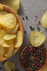 Pile of crispy potato chips with spices lying  on in a wooden bowel. Concept of fast food background. Free place for text, top view.