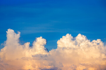 Fototapeta na wymiar Big White fluffy cumulonimbus storm clouds in deep blue sky at sunset