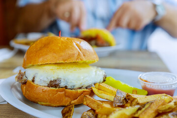 Hamburger with cheese and fried potatoes on a table