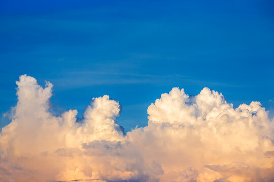 Big White fluffy cumulonimbus storm clouds in deep blue sky at sunset © nutt