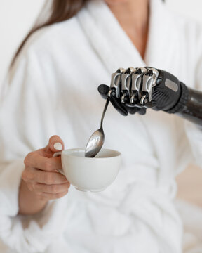 Girl with a prosthesis stirring coffee with a spoon