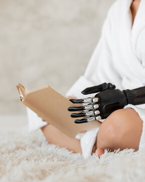 A girl with a prosthesis on her arm is reading a book