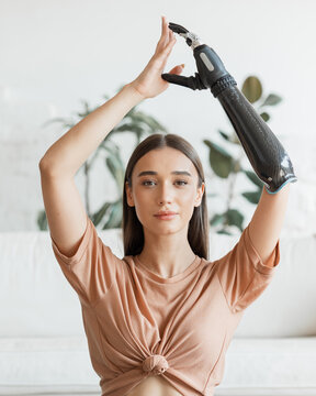 Woman with a prosthesis on her arm doing yoga at home