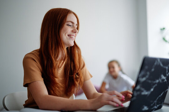 Smiled girl using laptop for doing her home task