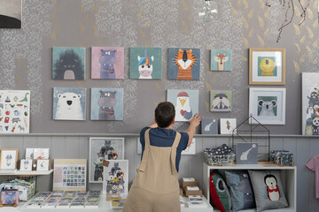 Young Illustrator Hanging Canvas On The Wall 