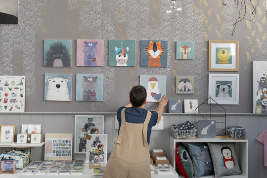 Young Illustrator Hanging Canvas On The Wall 