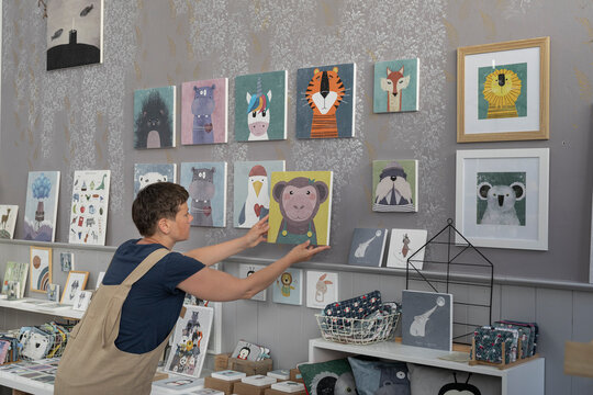 Young Illustrator Hanging Canvas On The Wall 