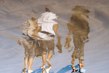 Fototapeta premium Reflection of 3 people on the shore of the beach