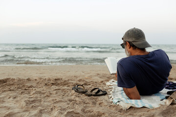 Naklejka premium Man reading at the beach