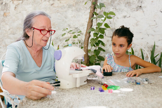 Woman teaching a kid how to use a sewing machine