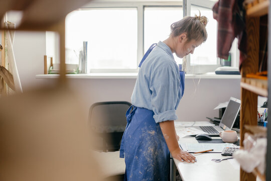 Craftswoman in an apron in the office at work