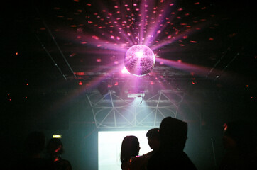 Anonymous people dancing and a purple mirrorball