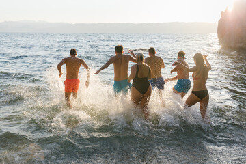 Group of friends running into the water