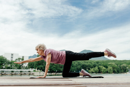 Senior woman doing gymnastics near lake