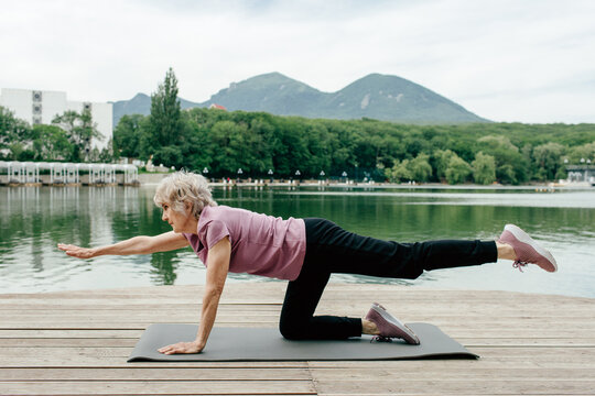 Senior woman doing gymnastics near lake