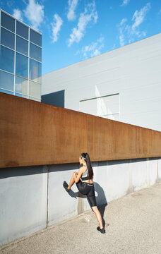 Active woman stretching legs near wall