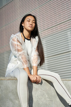 Young woman in sporty outfit sitting on concret